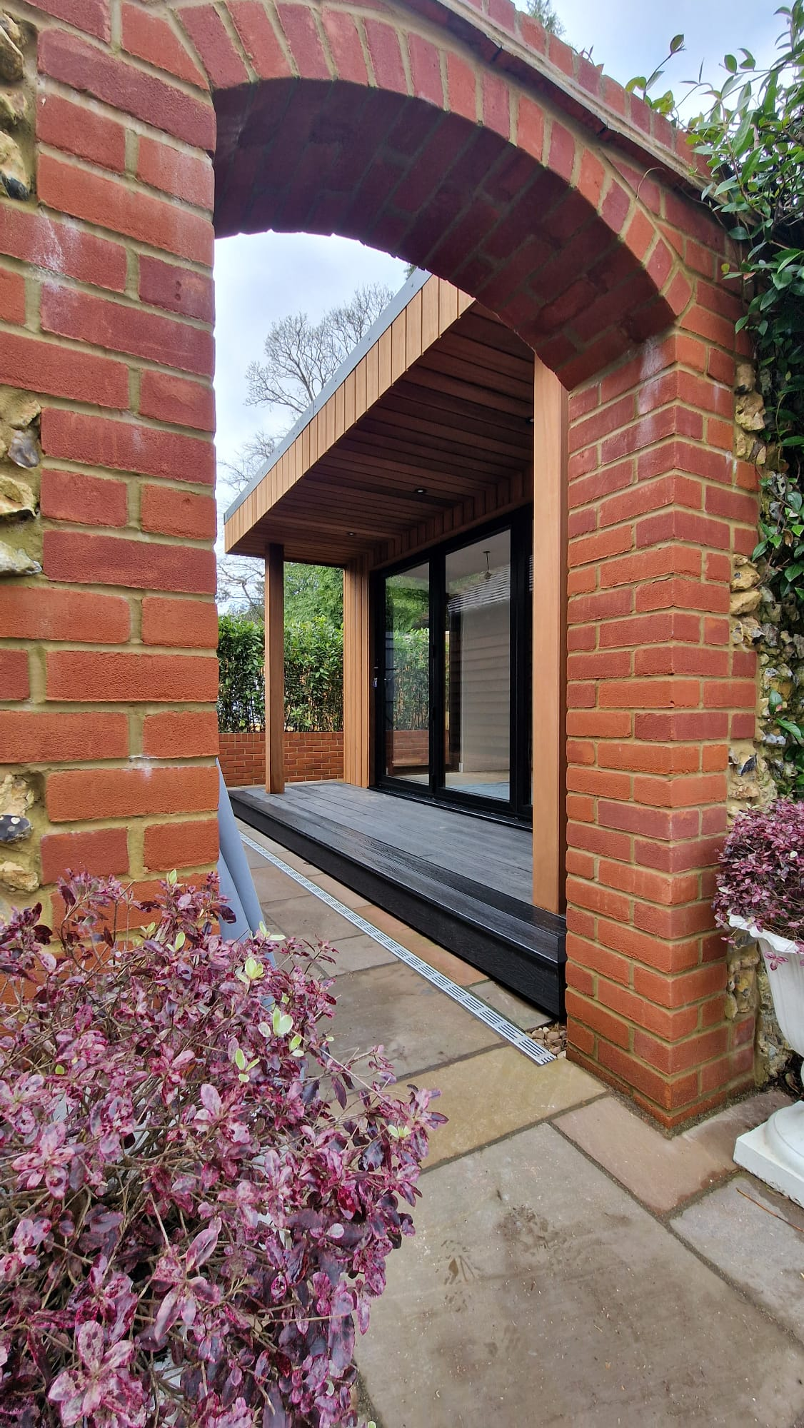 Bespoke garden room viewed through a brick garden arch